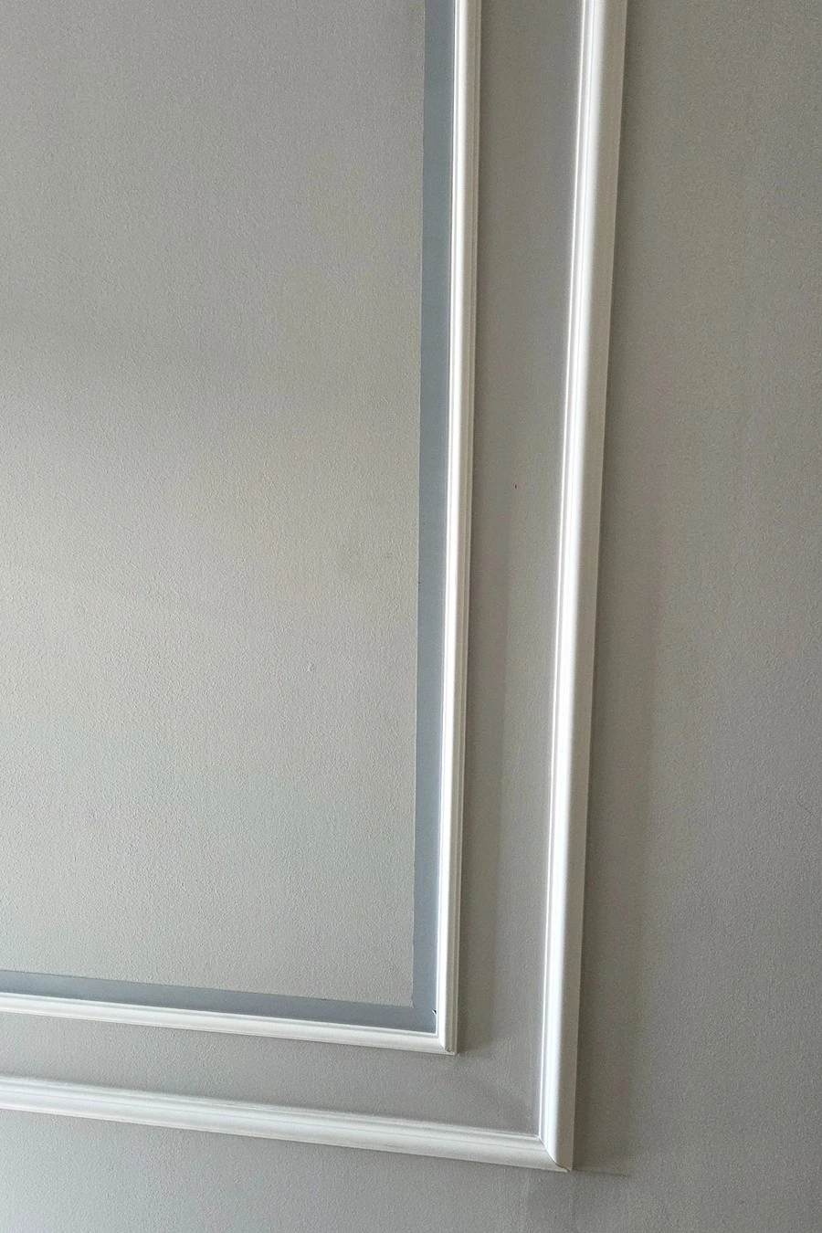 Platbandă decorativă din inox fixată vertical pe perete, cu folia de protecție încă aplicată